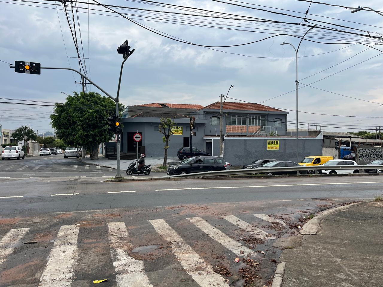 Cruzamento semaforizado em frente ao imóvel, com carros parados no sinal