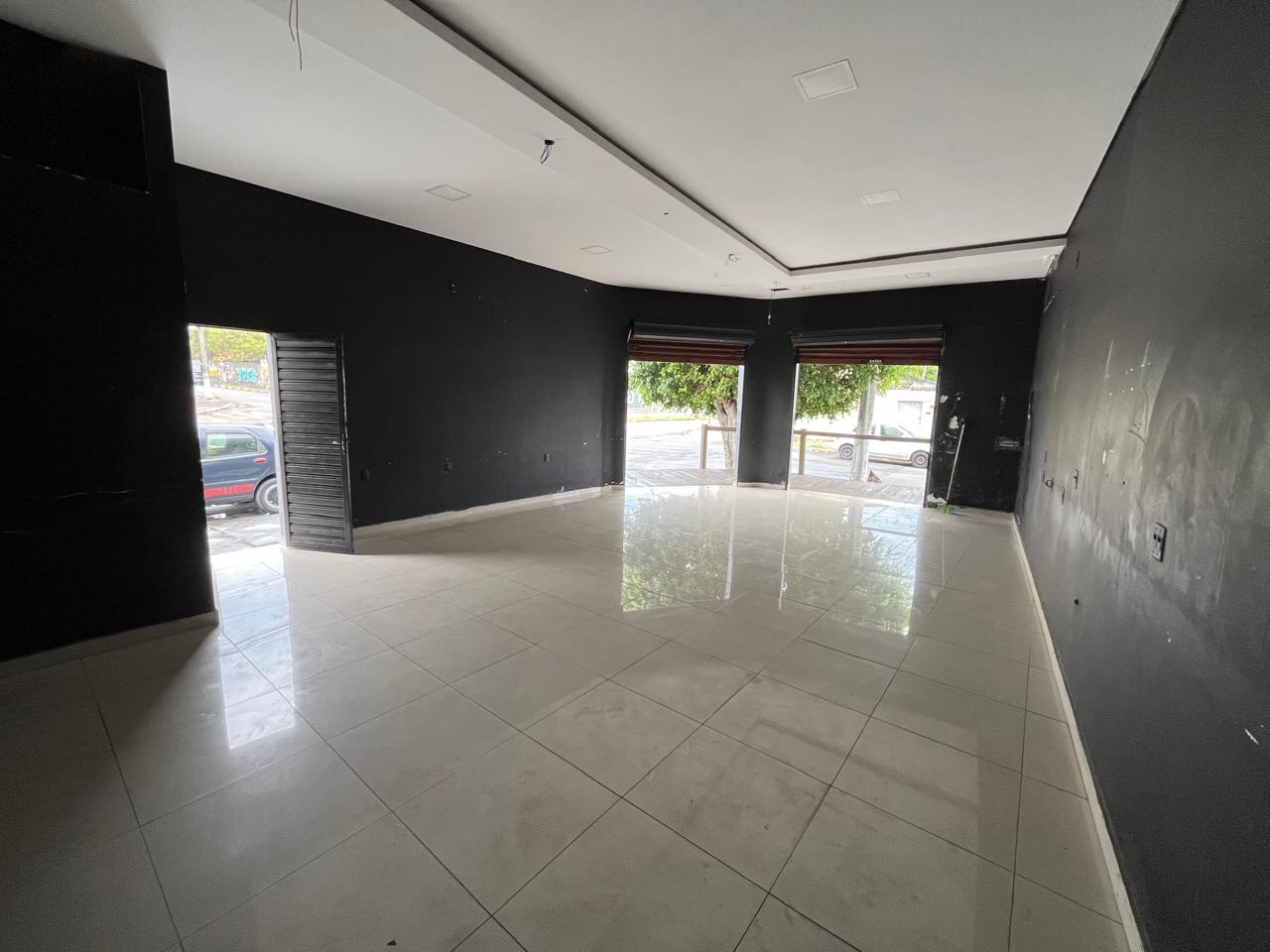 Interior do salão comercial, com piso porcelanato claro, forro de gesso e duas vitrines abertas para a rua